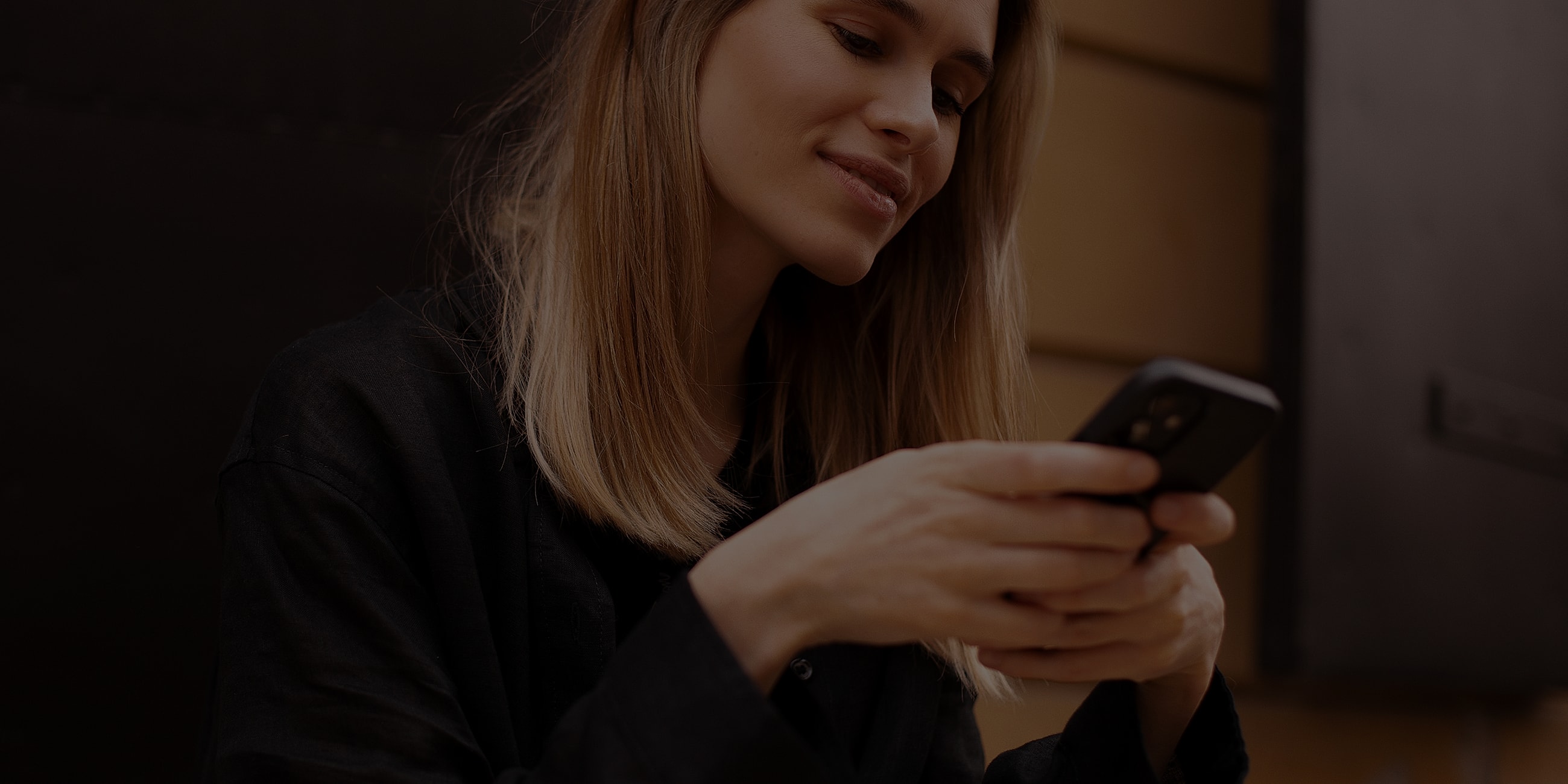Woman using smartphone, smiling, casual setting.