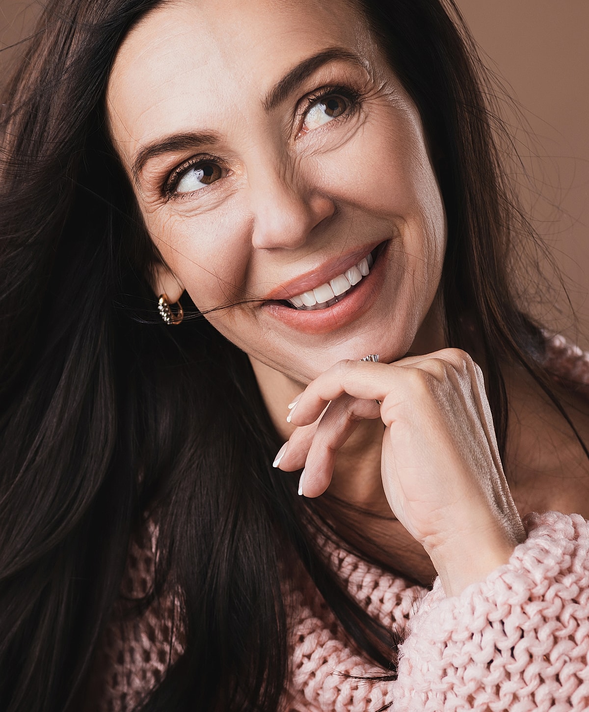 Smiling woman with long hair in soft sweater.