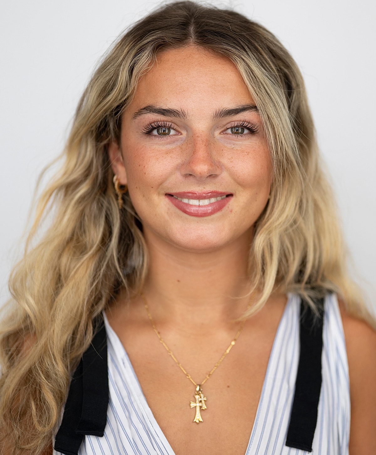 Smiling woman with wavy hair and necklace.