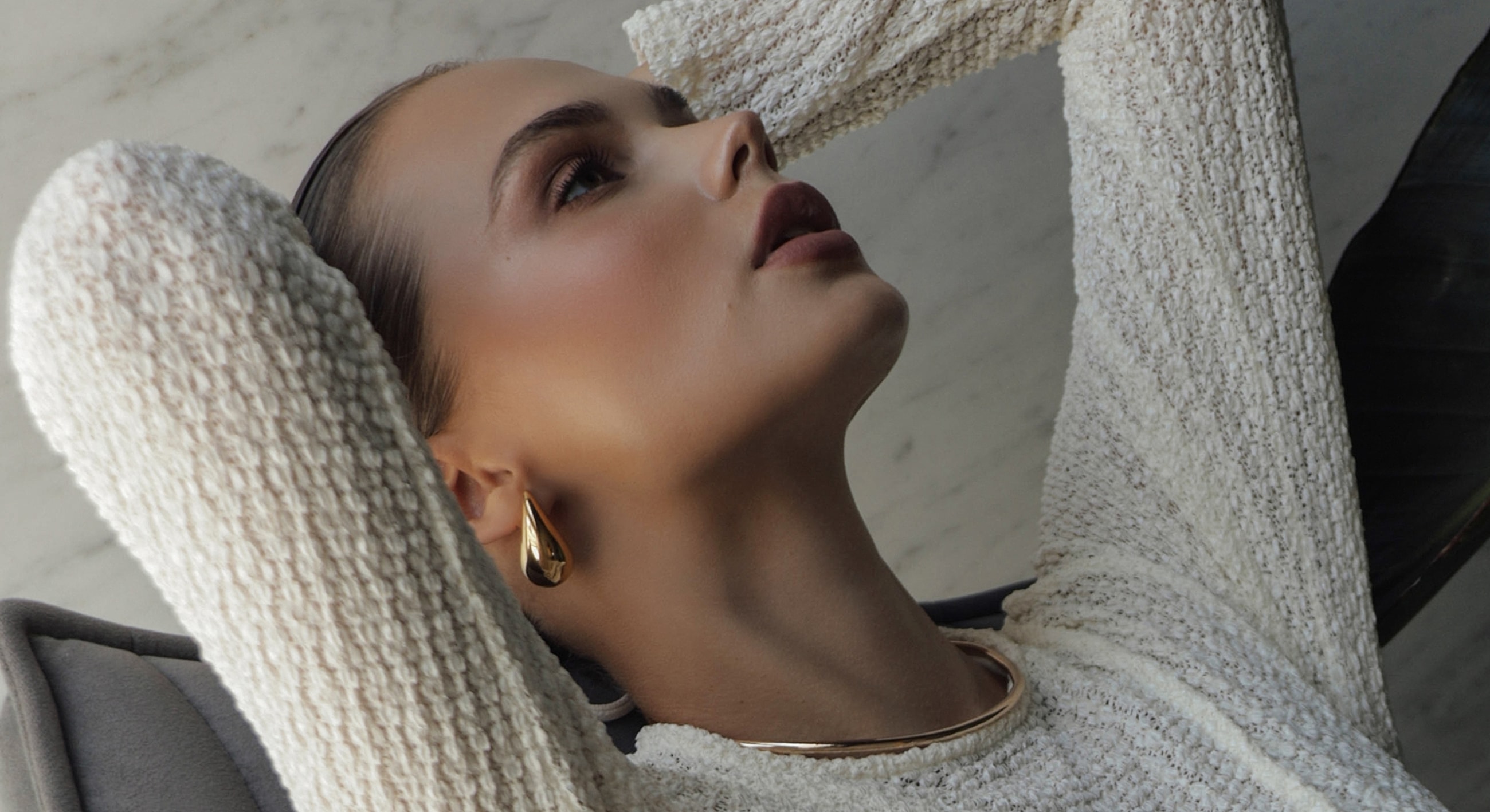 Woman in textured sweater with elegant jewelry.