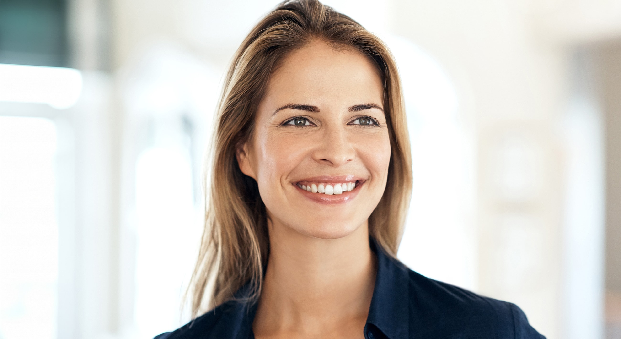 Smiling woman with long hair and natural lighting.