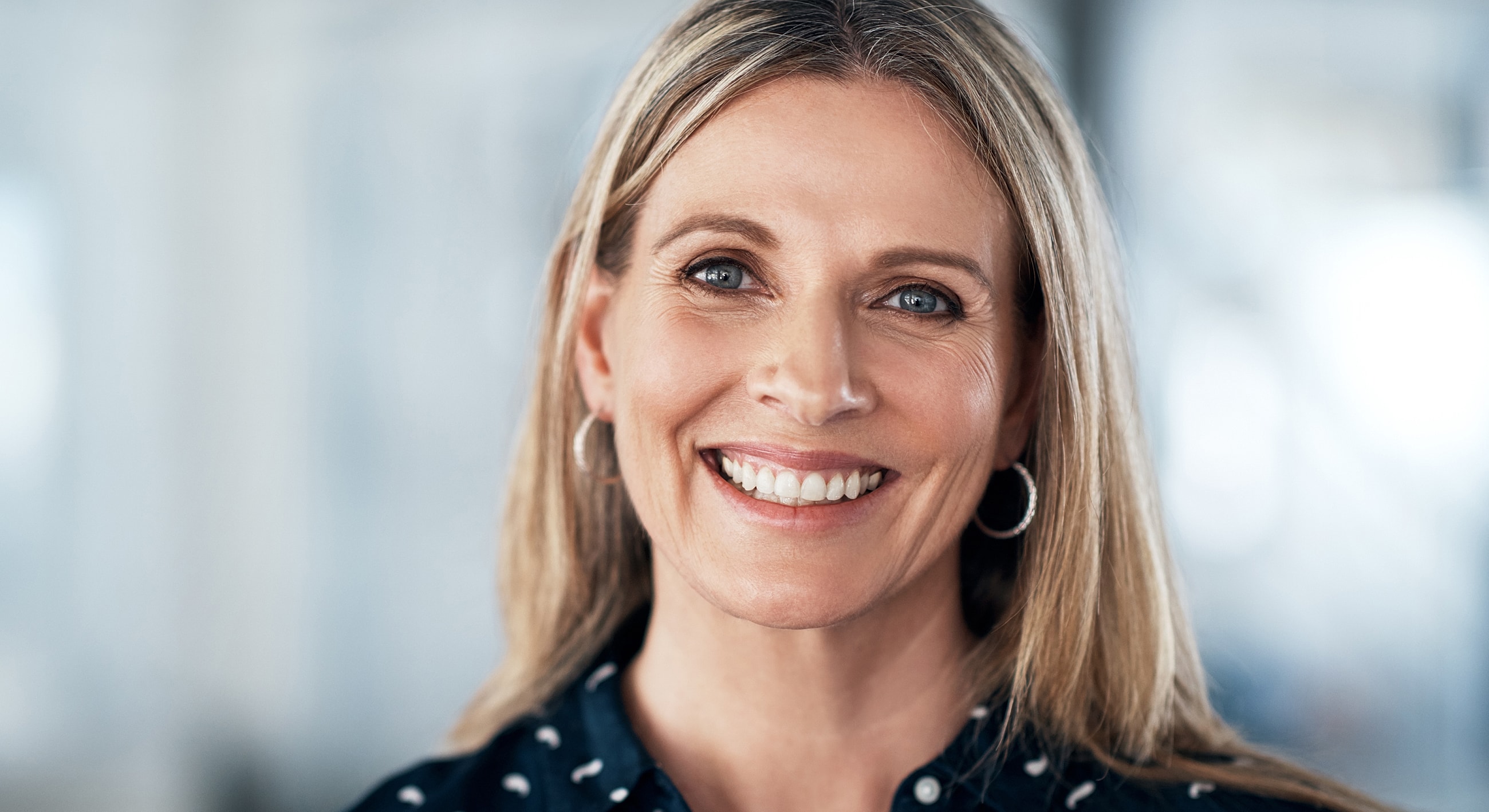 Smiling woman with blonde hair and earrings.